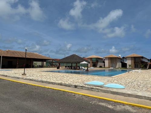 a swimming pool with huts on the side of a road at Casa Praia dos Carneiros in Tamandaré