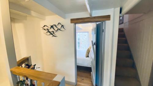 a hallway with a mirror and a staircase with a bed at SPINDRIFT is A Beautiful Newly Refurbished THREE BEDROOM Private Family House located on the OLD HARBOUR and the COASTAL PATH in the Heart of Beautiful POLPERRO in Polperro