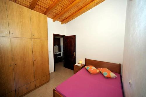 a bedroom with a pink bed and wooden cabinets at FOUR INDEPENDENCE HOUSES BY THE SEA in Glida