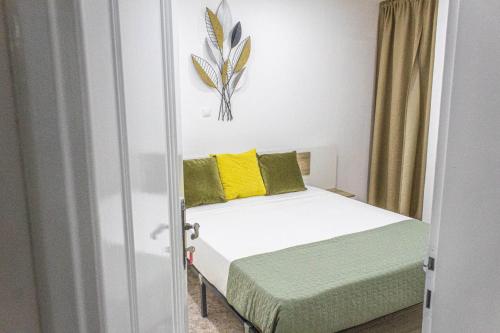 1 dormitorio con 1 cama con almohadas amarillas y verdes en Apartamento Mágico p/ momentos Memoráveis, en Santa Maria