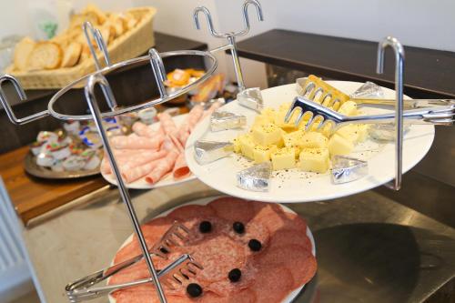 two plates of food on a buffet with cheese and bread at Hotel Vila Katrca in Ljubljana