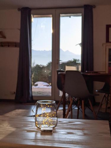 un bocal en verre avec des lumières sur une table devant une fenêtre dans l'établissement Appartement de plain-pied en montagne avec vue merveilleuse sur le massif de Belledonne, à Saint Bernard du Touvet