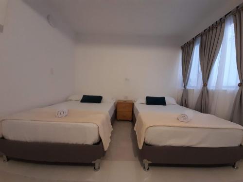 duas camas num quarto com janelas e cortinas em Road Living Home em Medellín