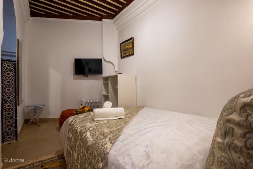 a bedroom with a bed and a tv on the wall at Riad Bin Souaki in Chefchaouene