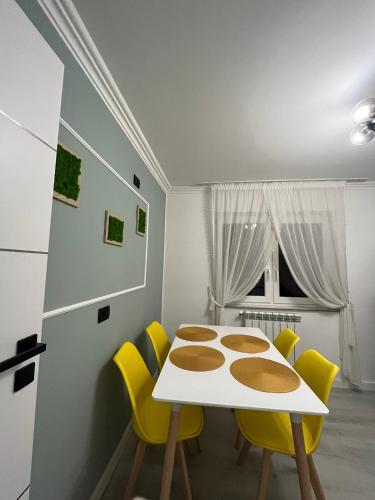 une salle à manger avec une table blanche et des chaises jaunes dans l'établissement Ely Apartaments, à Borşa