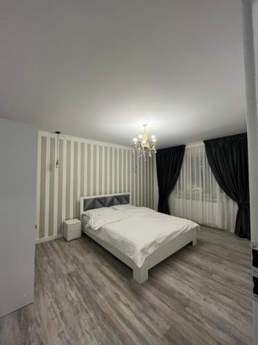 - une chambre avec un lit blanc et un lustre dans l'établissement Ely Apartaments, à Borşa