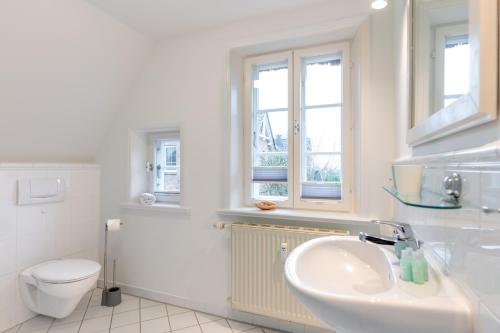 a white bathroom with a sink and a toilet at Reethus WE 4, Seeschwalbe in Borgsum