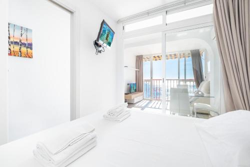 sypialnia z białym łóżkiem i dużym lustrem w obiekcie Las Damas 14-B Sea View Levante Beach w mieście Benidorm