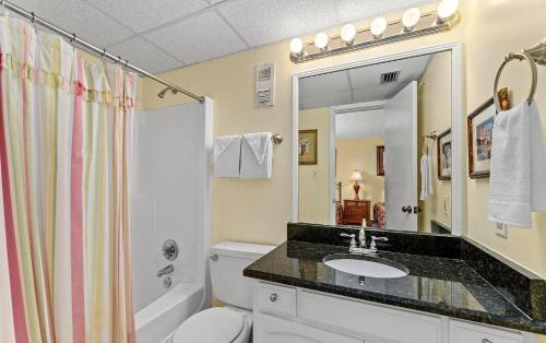 a bathroom with a sink and a toilet and a mirror at Sugar Beach Condo in Panama City Beach