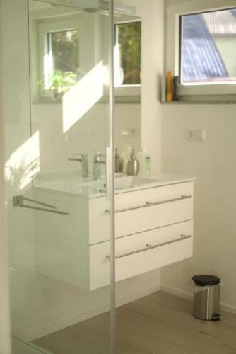 a white bathroom with a sink and a mirror at Sehr beliebt! Ferienhaus zur Donau in Herbertingen