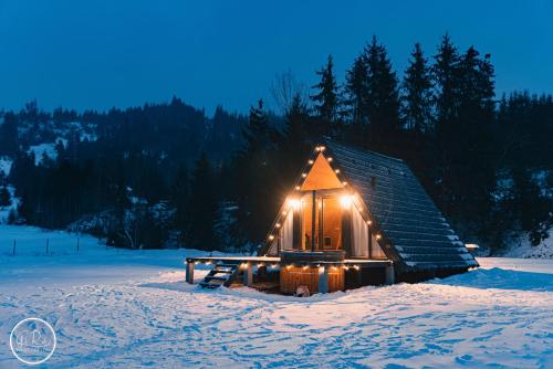 una pequeña cabaña de madera en la nieve por la noche en SouL EsCaPe, en Bălan