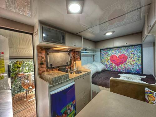 an rv with a kitchen and a bed in it at Recanto Lira II in Monte Verde