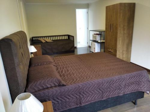 een slaapkamer met een groot bed en een bank bij Suíte dprata in Campos do Jordão