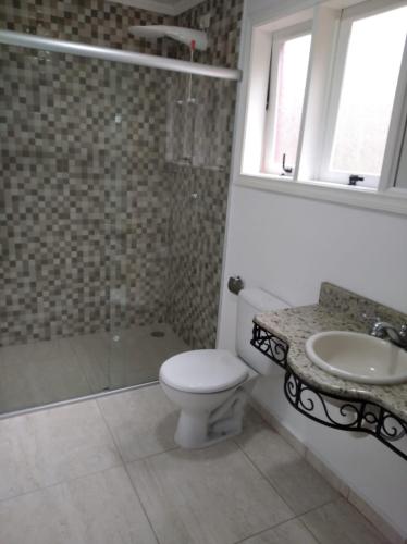een badkamer met een toilet, een wastafel en een douche bij Suíte dprata in Campos do Jordão