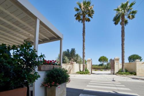 deux palmiers devant un bâtiment avec des plantes dans l'établissement Hotel dei Messapi, à Muro Leccese