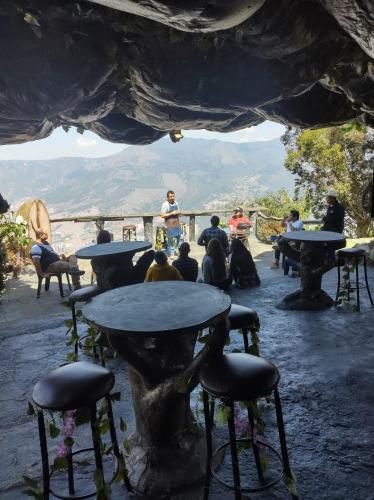 a group of people sitting at tables with mountains in the background at Cabaña Parque Arvi vista panorámica in Medellín