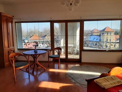 a living room with a table and chairs and a balcony at Magda Vendégház in Tokaj