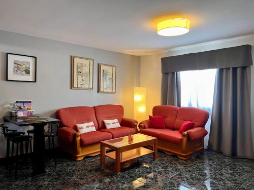 a living room with two red chairs and a table at Apartamentos Dalia in Vecindario