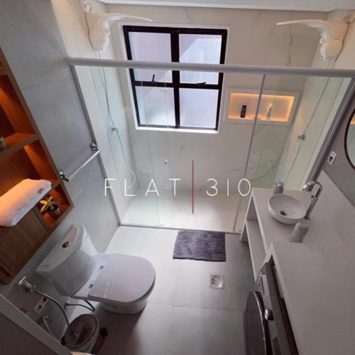 a bathroom with a toilet and a sink and a window at flat em são vicente in São Vicente