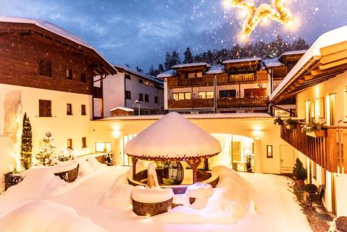 a building with a gazebo in the snow at Aparthotel Kastel Seiser Alm in Castelrotto