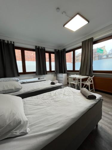 a bedroom with two beds and a table and windows at @Home Zimmervermietung Hamburg in Hamburg