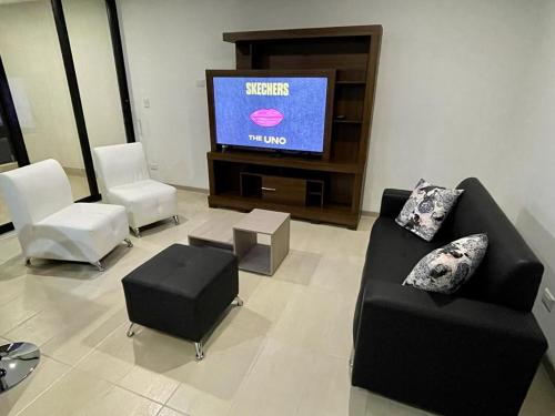 un soggiorno con sedie e TV a schermo piatto di Apartamento Amoblado en Manizales a Manizales