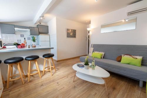 a living room with a couch and a table and stools at L'Auguière Est, maisonnette sans vis-à-vis et au calme avec vue sur les vignes in Hyères