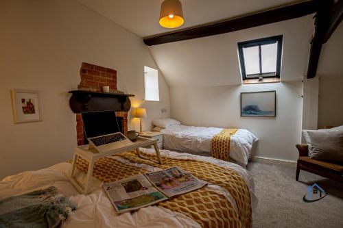 um quarto com 2 camas e um computador portátil numa secretária em The Old Plough, rustic flat, super king bed or twins, en-suite, secure parking, free wi-fi, corporates welcome em Caldecott