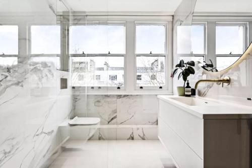 a white bathroom with a sink and a mirror at Luxurious flat with four bedrooms in London