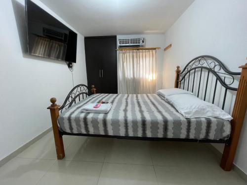 1 dormitorio con 1 cama y TV en la pared en Apartamento en Santa Marta donde Jesús 1, en Santa Marta
