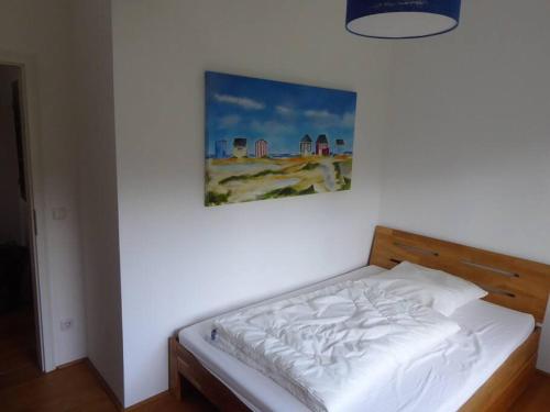 un letto in una camera da letto con un dipinto sul muro di Erholung auf dem Land zwischen Ostsee und Schlei a Stoltebüll
