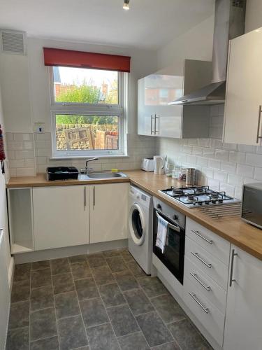 a kitchen with a stove and a washer and dryer at Isandula The Home from Home in Nottingham