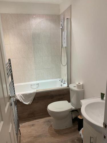 a bathroom with a toilet and a tub and a sink at Isandula The Home from Home in Nottingham