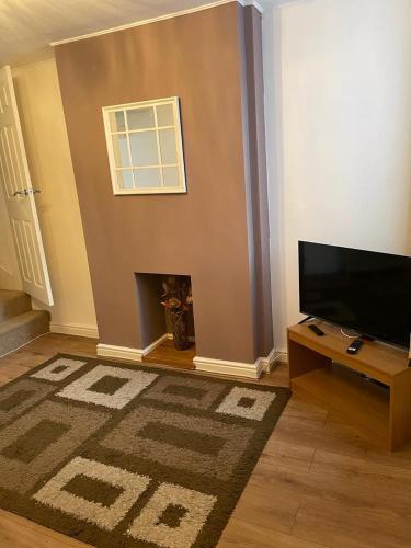 a living room with a flat screen tv and a fireplace at Isandula The Home from Home in Nottingham