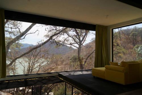 un soggiorno con una grande finestra e un divano di Loft hermoso entre el bosque, vista al Lago. a Valle de Bravo