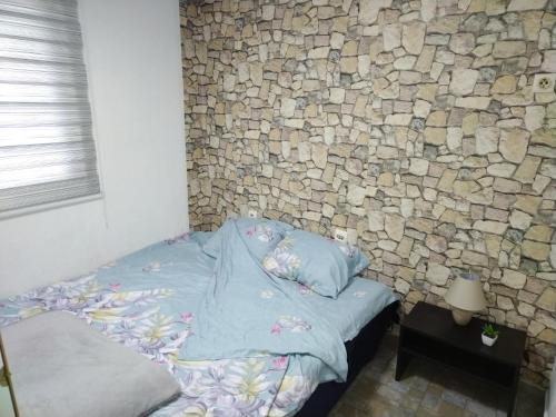 Ce lit se trouve dans un dortoir doté d'un mur en pierre. dans l'établissement SAN, à Vranje