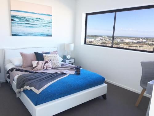 a bedroom with a bed and a large window at Salt at Oceanside in Kawana Waters