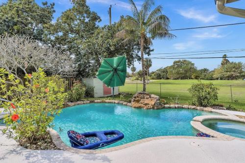 a swimming pool with an umbrella in a yard at Pool Heat I Firepit and BBQ I 75"TV I Foosball I 581mbps in Cooper City