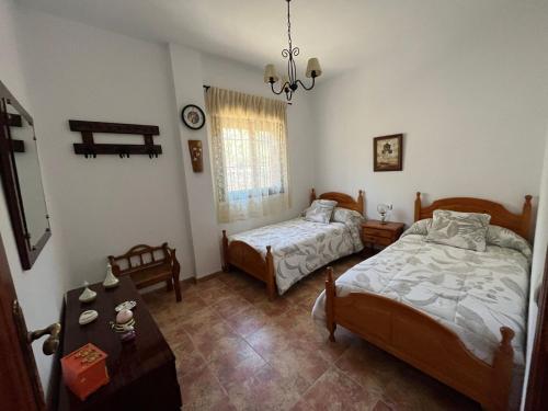 1 dormitorio con 2 camas, mesa y ventana en Casa La Era de Abdalajis-Caminito del Rey, en Valle de Abdalajís