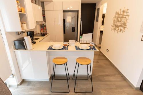 a kitchen with two stools at a kitchen counter at Apartamento moderno 1 habitación y 1 baño, área Cayalá Embajada USA in Guatemala
