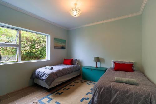 Un dormitorio con dos camas y una ventana. en Cherry on Top, en Morganʼs Bay