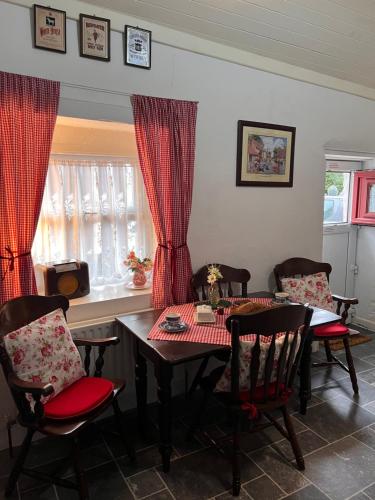 een eetkamer met een tafel en stoelen met rode gordijnen bij Tosses Cottage - Secluded cottage with hot tub in Newry
