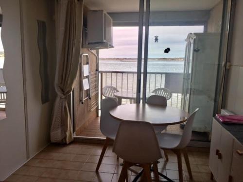- une table et des chaises dans la cuisine avec vue sur l'océan dans l'établissement APPARTEMENT COSY FRED FLAMANTS ROSES, à Balaruc-les-Bains