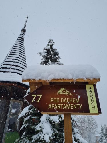 a sign in the snow in front of a church at Apartamenty Pod Dachem in Lutowiska
