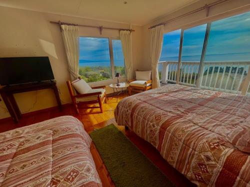 a bedroom with two beds and a large window at Hostal Casa Grande in Puerto Montt