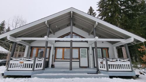 a small white house with a porch in the snow at Villa Aurora, Himos in Jämsä