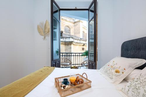 a basket of fruit on a bed with a window at Luxury Gran Via Apartments in Granada