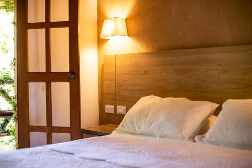 a bedroom with a bed with a wooden headboard and a lamp at Portales del Tayrona Garden Hotel in Calabazo