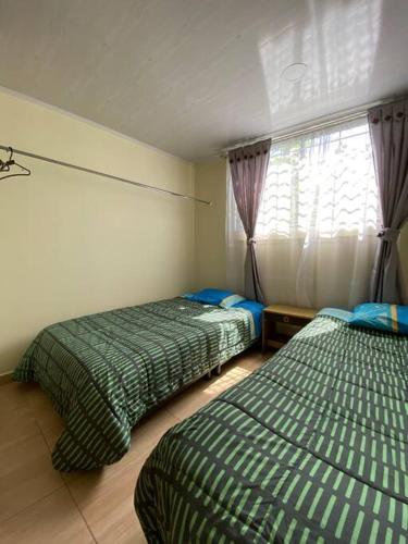 1 dormitorio con 2 camas y ventana en Apartamento San Gabriel, en Paipa