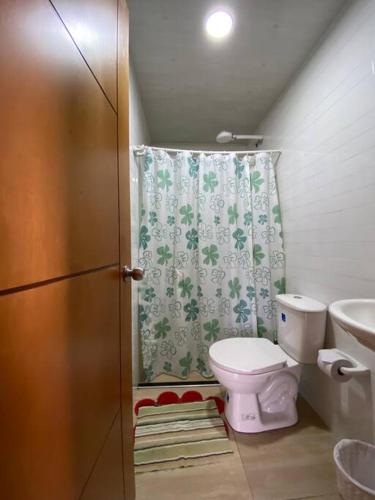 y baño con aseo y cortina de ducha. en Apartamento San Gabriel, en Paipa